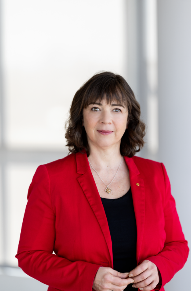 Eine brünette Frau in einem roten Blazer.
