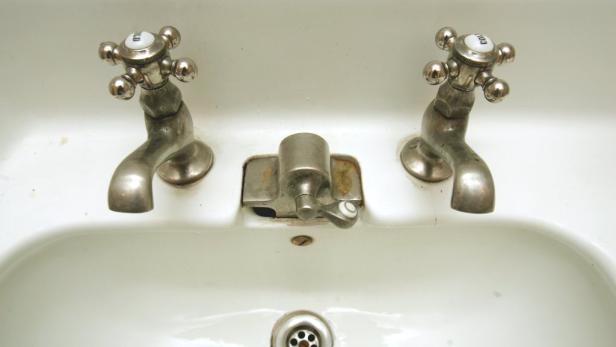 Ein Waschbecken mit zwei Wasserhähnen für kaltes Wasser und einem mittigen Abfluss.