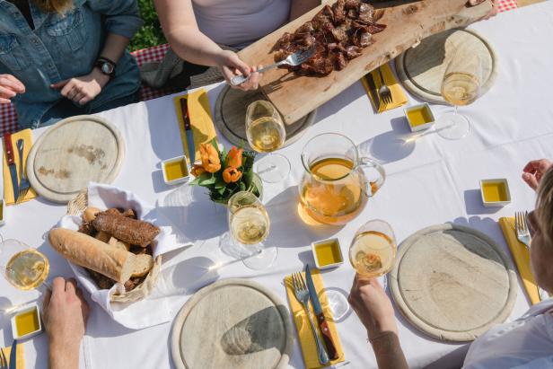 Ein Tisch mit Brot, Wurst, Wein und Olivenöl für ein Picknick im Freien.