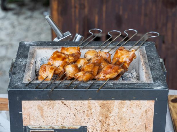 Fisch auf Spießen liegt auf einem Teriyaki-Grill.