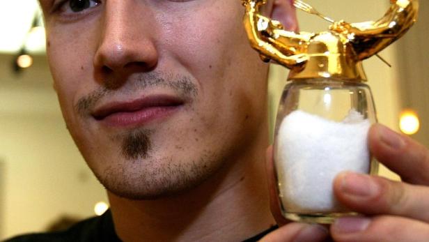 Ein Mann hält einen Salzstreuer mit einer goldenen Figur eines Gewichthebers.