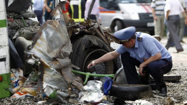 Ein Polizist untersucht die Trümmer eines zerstörten Fahrzeugs.