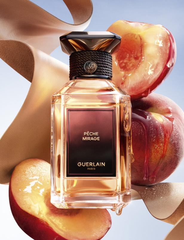 Eine Flasche „Pêche Mirage“ von Guerlain mit Pfirsichstücken und einem beigen Band.