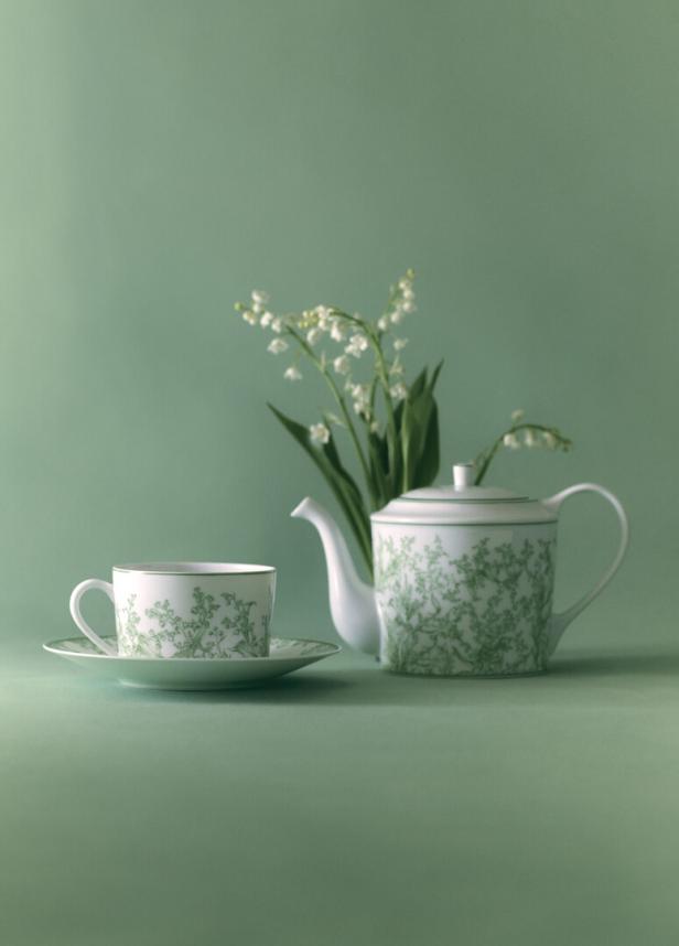 Eine Teetasse und eine Teekanne mit Maiglöckchenmuster stehen neben einem Strauß Maiglöckchen.