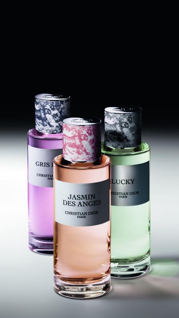 Drei Flakons verschiedener Düfte von Christian Dior stehen auf einem Tisch.