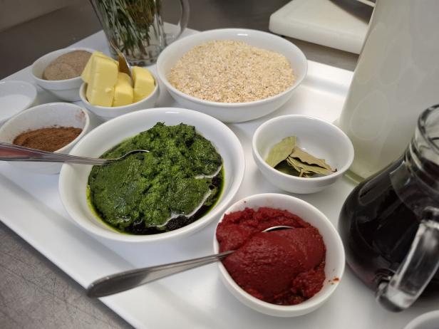 Verschiedene Zutaten wie Pesto, Tomatenmark und Gewürze sind auf einem Tablett angerichtet.