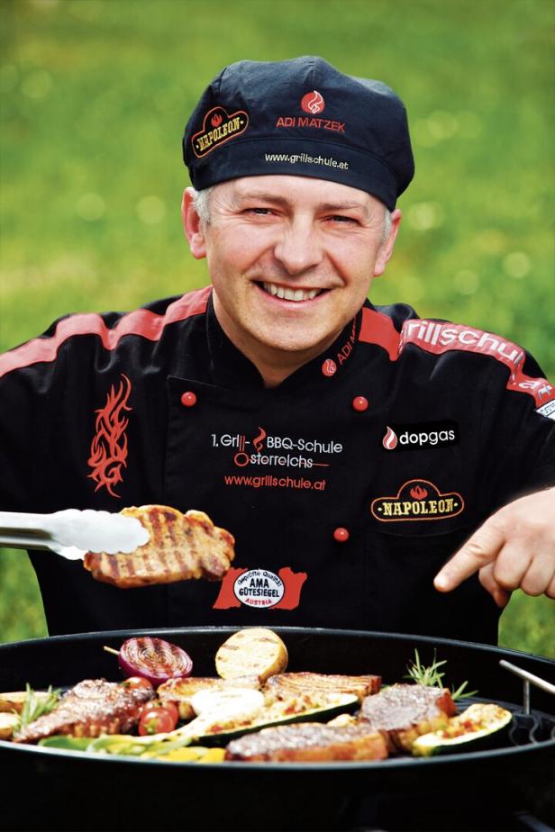 Ein lächelnder Koch von „www.grillschule.at“ grillt Fleisch und Gemüse.
