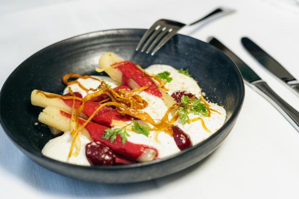 Spargel mit Rote Bete-Sauce und Kräutern in einer schwarzen Schale angerichtet.