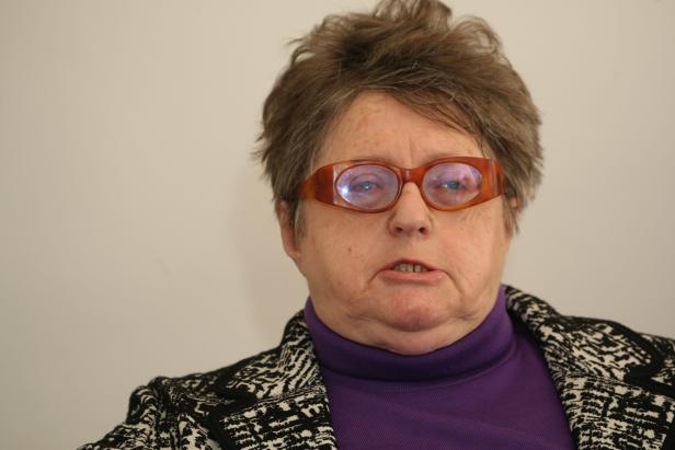 Eine Frau mit braunen Haaren und auffälliger Brille blickt in die Kamera.