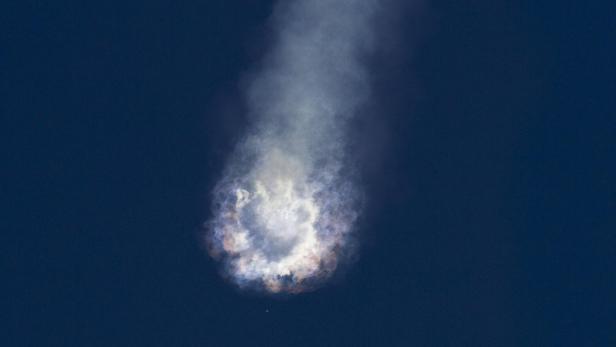 Eine Rauchwolke mit Flammen vor einem tiefblauen Himmel.