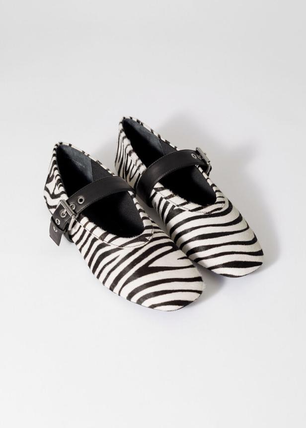 Zwei Mary-Jane-Schuhe mit Zebra-Muster und schwarzen Riemen stehen auf einem weißen Hintergrund.