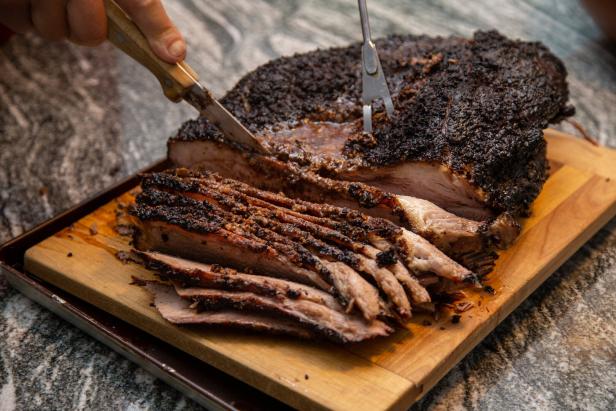 Beef Brisket frisch aus dem Smoker wird auf einem Holzbrett angeschnitten.