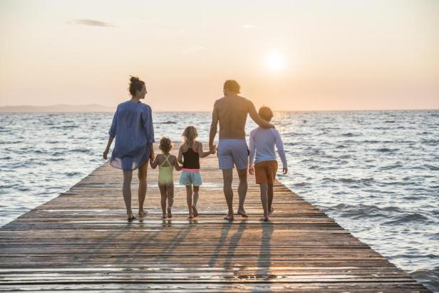 Eine fünfköpfige Familie läuft über einen Steg am Meer.