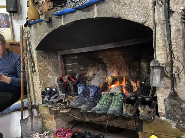 Pilger trocknen ihre Wanderschuhe an einer Feuerstelle.