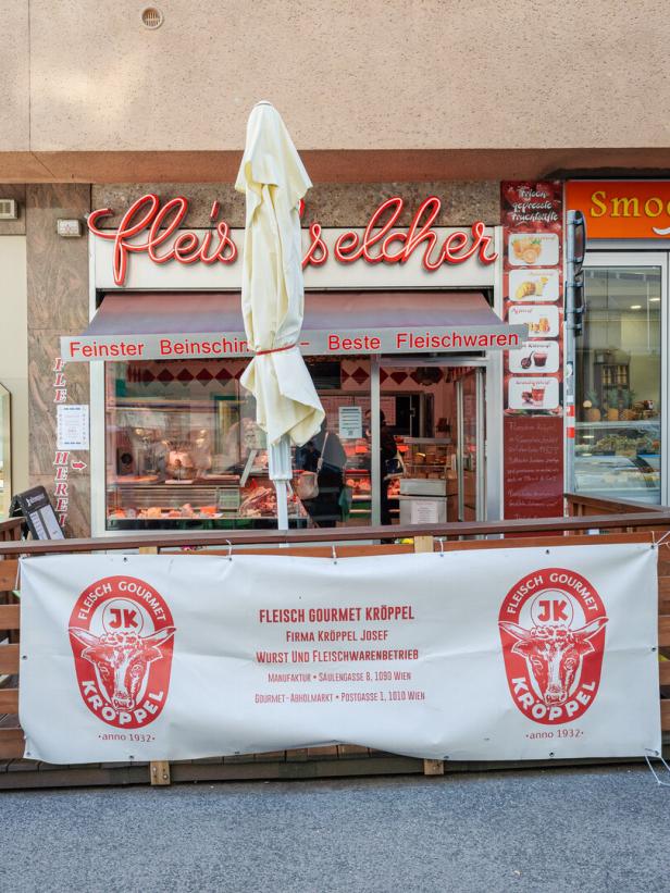 Ein „Fleisch Gourmet Kröppel“-Geschäft mit einem Werbebanner davor.