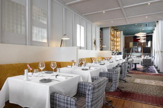 Ein elegant gedeckter Tisch in einem hellen Restaurant mit karierten Stühlen.
