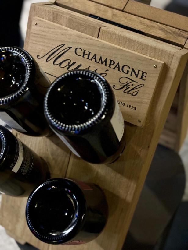 Mehrere Champagnerflaschen in einer Holzkiste der Marke „Mousset Fils“.
