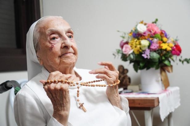 Die brasilianische Ordensfrau Inah Canabarro Lucas, mit einem Rosenkranz vor einem Blumenstrauß: Sie galt vom 29. Dezember 2024 bis zu ihrem Tod am 30. April 2025 als ältester lebender Mensch der Welt.