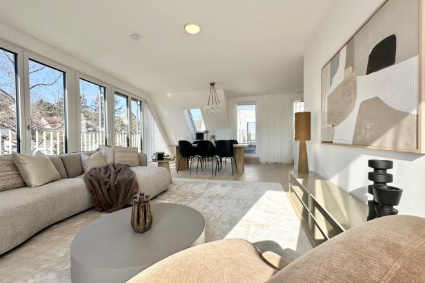 Modernes Wohnzimmer mit großen Fenstern und einer großen Couch, die einladend und hell wirkt.
