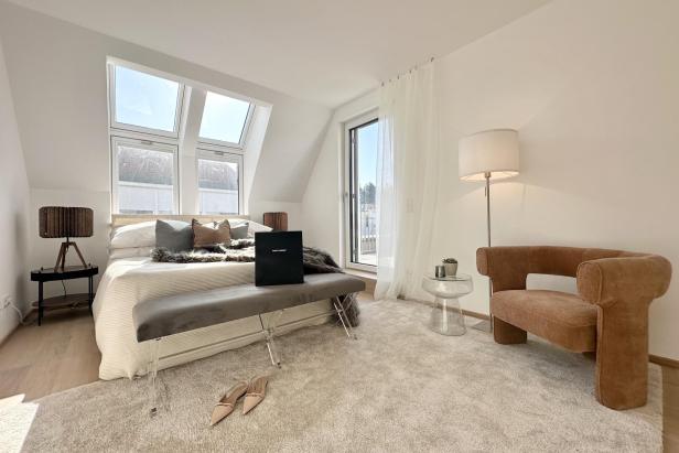 Schlafzimmer mit einem Bett, einem Stuhl und einem Fenster, das Tageslicht hereinlässt.