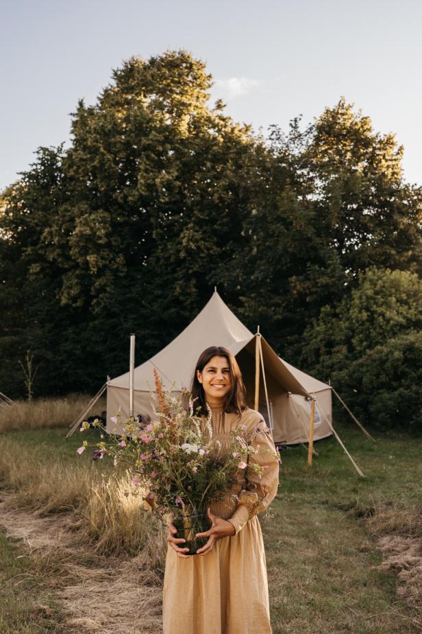 Eine Frau hält einen Blumenstrauß vor einem Zelt auf dem „Møns Klint Resort“.