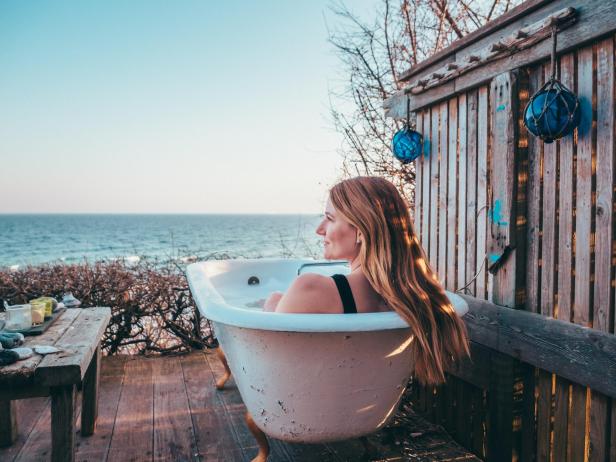 Eine Frau entspannt in einer Badewanne mit Blick auf das Meer im Møns Klint Resort.