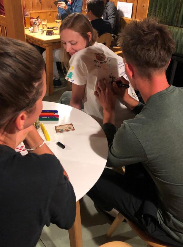 Männer schreiben auf ein Tshirt der Braut in einer Berghütte