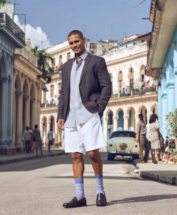 Ein Mann in Shorts, Sakko und Socken steht auf einer Straße in Havanna, Kuba.
