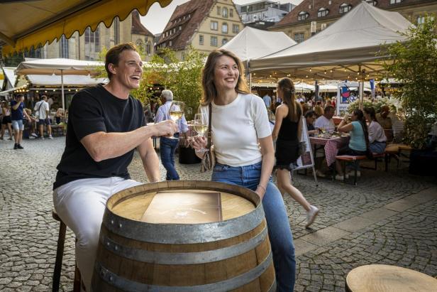 Ein Paar prostet sich auf dem Stuttgarter Weindorf mit Weißwein zu.