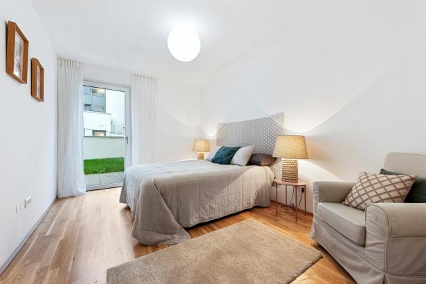 Ein helles Schlafzimmer mit Bett und Sessel. 