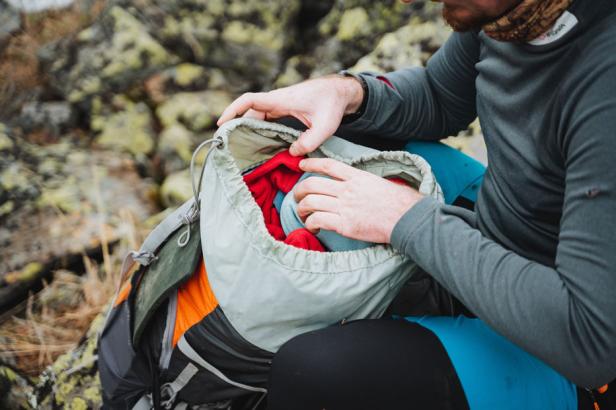 Ein Wanderer packt seinen Rucksack auf einem felsigen Untergrund.