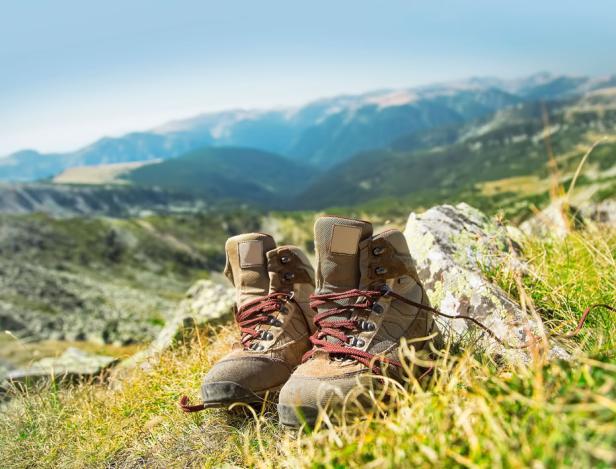 Wanderschuhe stehen auf einem Hügel mit Blick auf eine Berglandschaft.