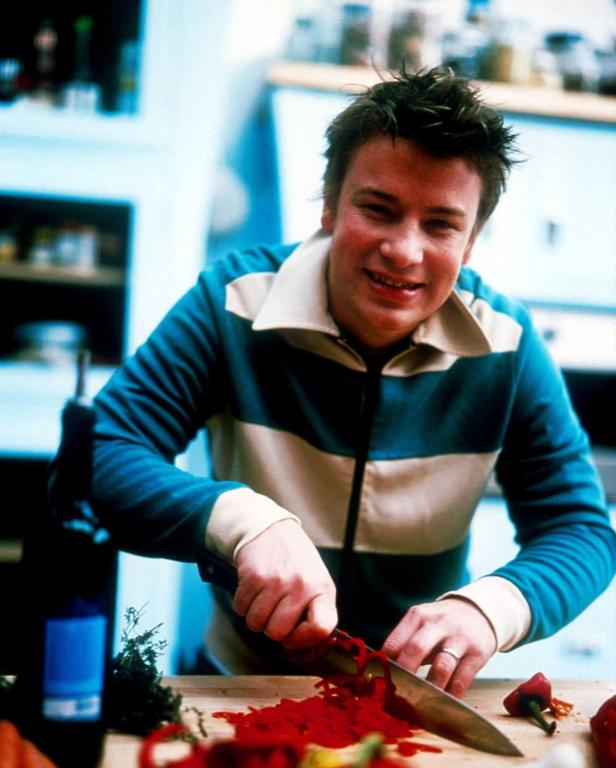 Jamie Oliver schneidet rote Paprika in einer Küche.
