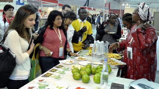 An einem Stand probieren mehrere Personen exotische Früchte und Speisen.