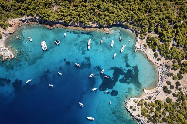 Luftaufnahme einer Bucht mit türkisfarbenem Wasser und mehreren Booten.