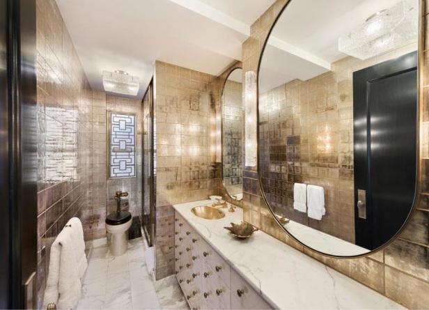 Ein Badezimmer mit goldenen Fliesen, einem großen Spiegel und Marmorarbeitsplatten.