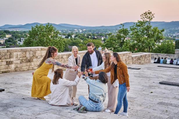 Gruppe von Freunden, die auf der Terrasse anstoßen und gemeinsam feiern.