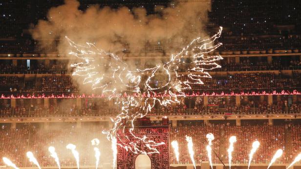Eine Feuer-Performance mit einem Phönix und einem Torbogen vor einer Zuschauermenge.