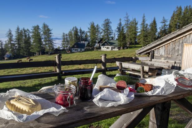 Frühstück im Freien vor der Hütte am Berg mit Wurst, Butter, Brot und Marmelade