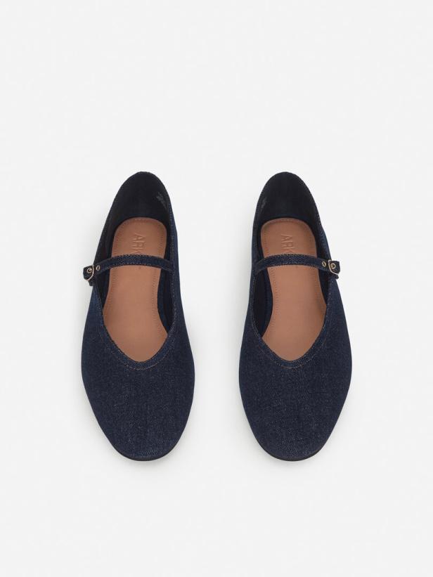 Zwei blaue Ballerinas aus Jeansstoff mit Riemchen auf einem weißen Hintergrund.