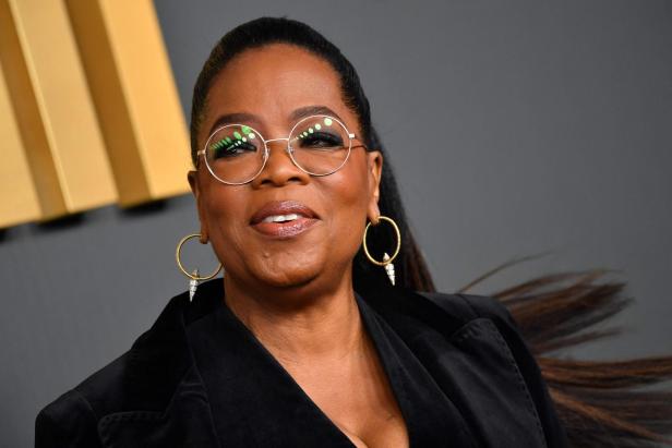 Oprah Winfrey mit runder Brille und goldenen Ohrringen.