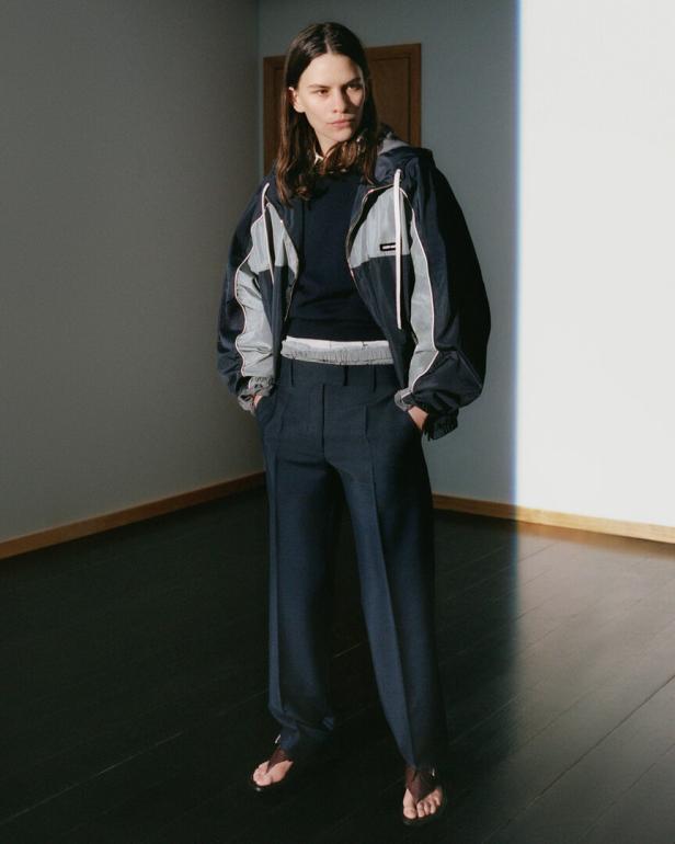 Eine Frau in einer blauen Jacke und Hose steht in einem Raum.