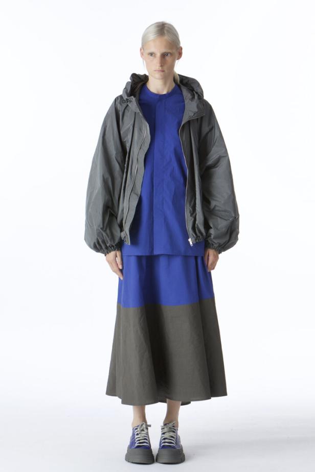 Eine Frau in einem blauen Kleid mit einer grauen Jacke und passenden Schuhen.
