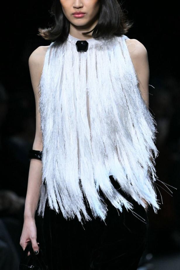 Ein Model präsentiert ein ärmelloses Oberteil mit Fransen von Armani.