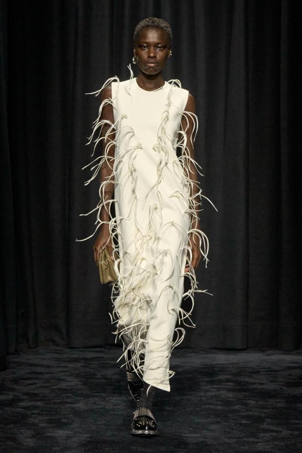 Ein Model präsentiert ein weißes Kleid mit Federapplikationen von Jil Sander Herbst/Winter 2025.