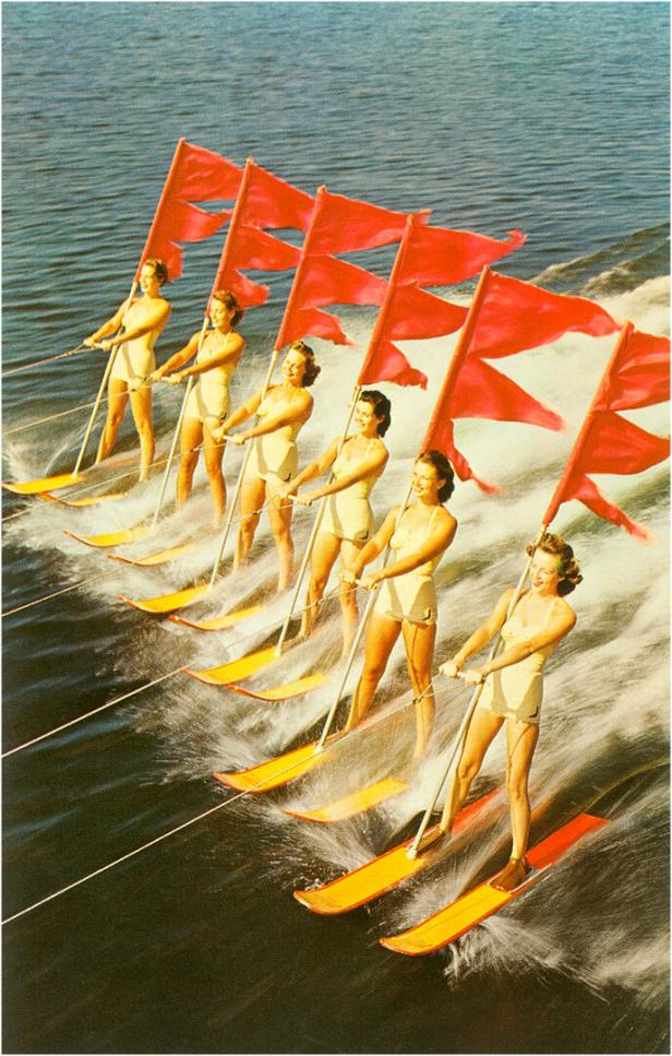 Eine Gruppe von Wasserskiläuferinnen zieht rote Flaggen auf dem Wasser.