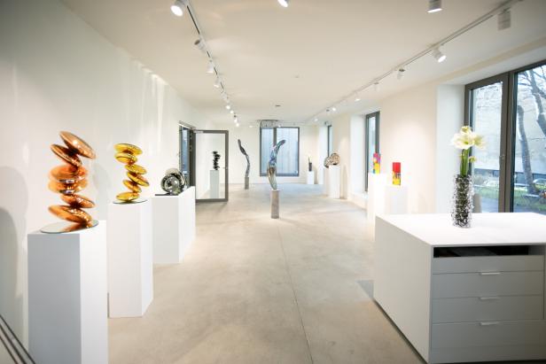 Eine Kunstausstellung mit verschiedenen Skulpturen in einem hellen Raum.