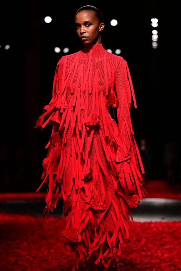 Ein Model präsentiert ein rotes Kleid mit Fransen auf dem Laufsteg einer Ferragamo-Modenschau.