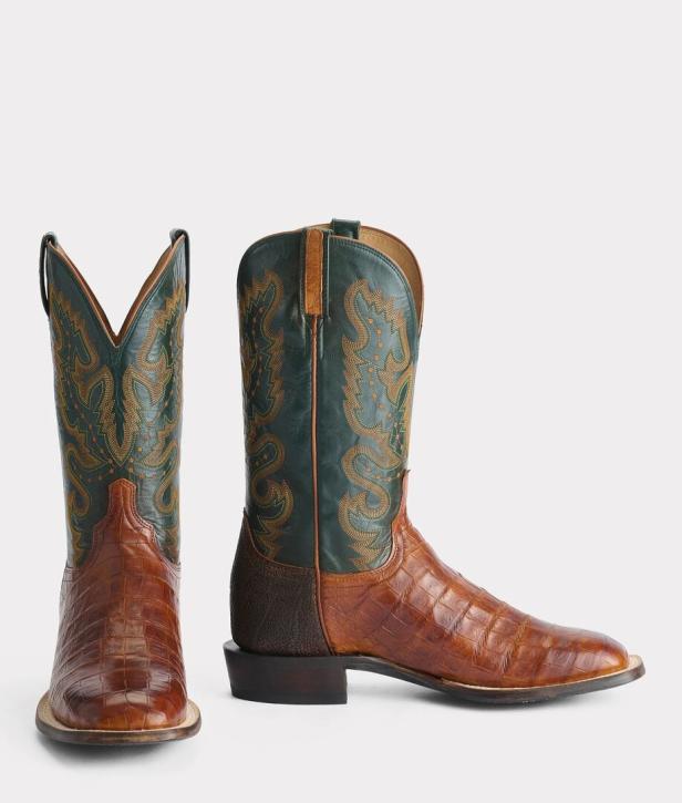 Zwei Cowboy-Stiefel aus braunem Krokodilleder mit grünen Akzenten stehen vor einem weißen Hintergrund.