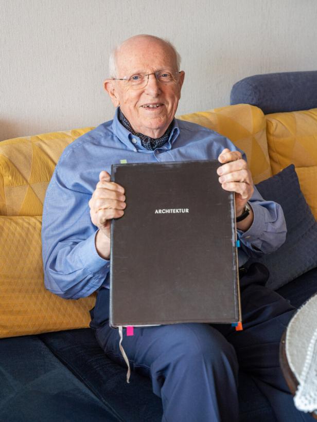 René Prassé hält ein Buch mit dem Titel „Architektur“ in den Händen.